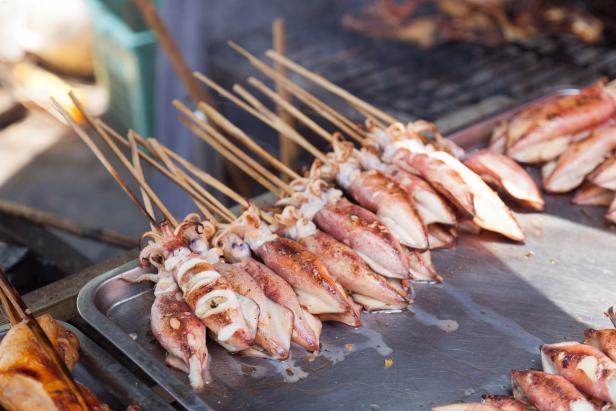Freshly grilled squid on sticks at a barbecue grill, sold at the crab market in Kep, Cambodia.