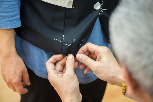 Hong Kong iStockalypse.  An Asian tailor checks the fit of a custom made outfit for a woman customer in Kowloon, Hong Kong.  The partially handmade vest has been hand basted and will be completed when final adjustments have been made.