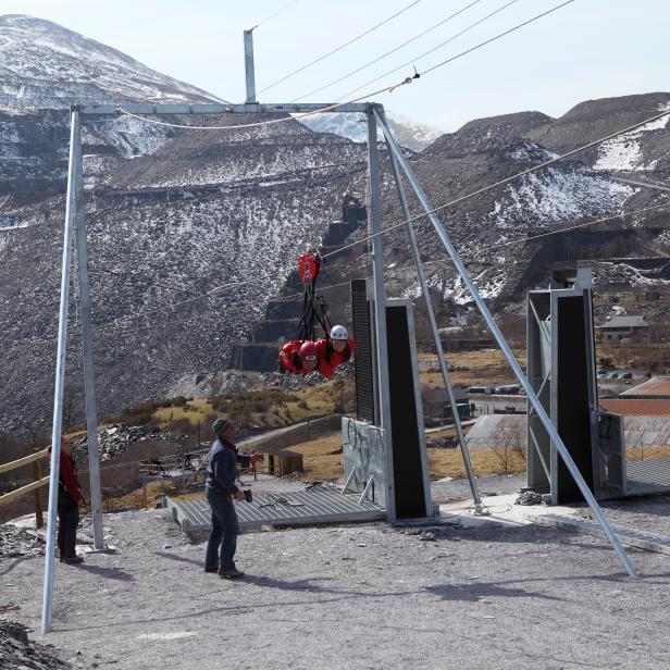 Two people come in to end a tandem ride on the Big Zipper of Zip World, which runs over Penrhyn Quarry at Bethesda in Wales. The 1600 metre (one mile) long zip wire is the longest in the northern hemisphere.