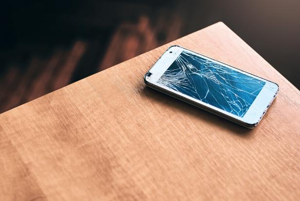 Smartphone with broken screen on the wooden table
