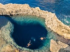 Deep blue hole at the world famous Azure Window in Gozo island - Mediterranean nature wonder in the beautiful Malta - Unrecognizable scuba divers swimming to adventure water cave