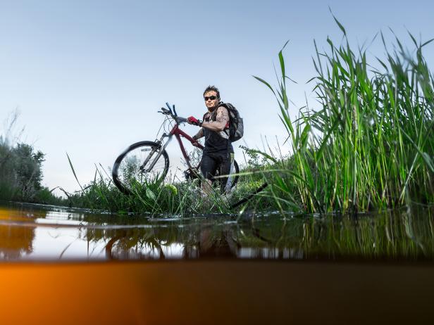 Young athlete crossing the river with bicycle