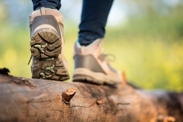 Close up outdoor shoes of a female hiker walking on log.