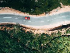 Aerial view on  red car on the road near green tea plantation in mountains in Sri Lanka